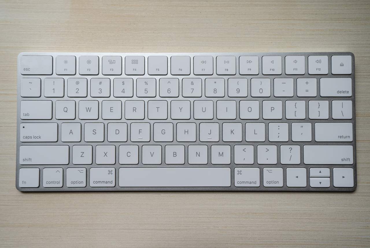 teclado apple branco sobre fundo de madeira