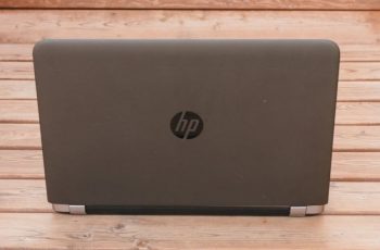 Notebook HP com a tela aberta sobre piso de madeira