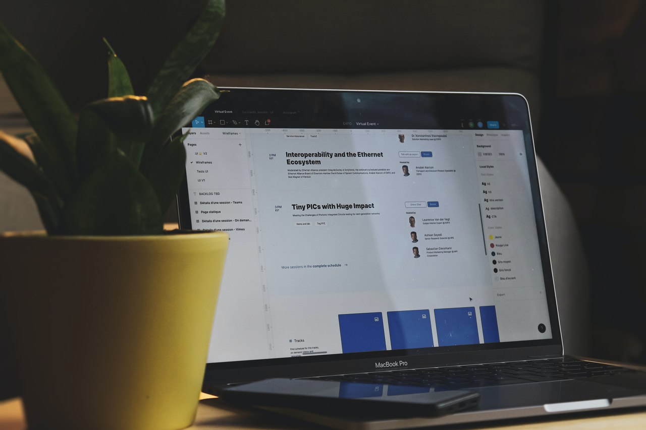 Notebook com tela escura ao lado de uma planta sobre uma mesa
