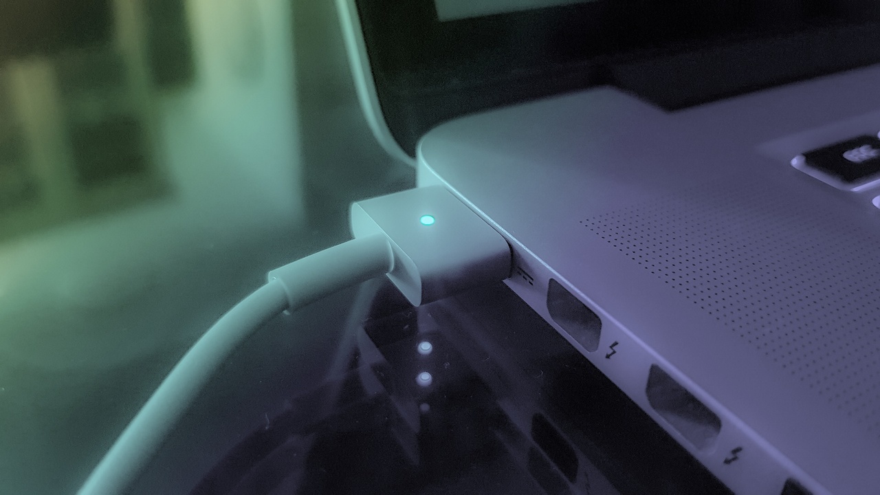 carregador de bateria de notebook conectado em um macbook com a luz verde acesa