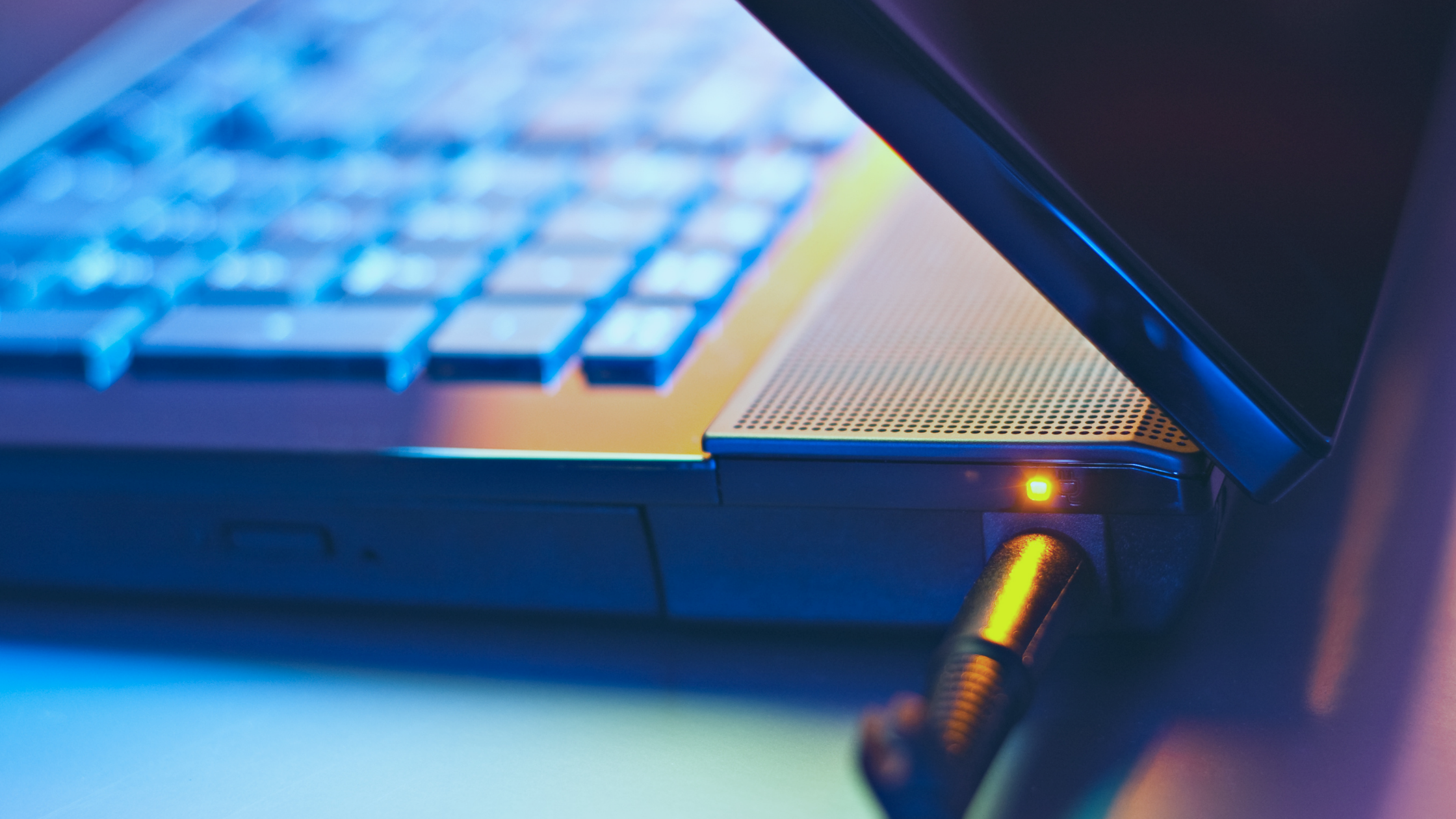 Imagem de um notebook entreaberto com o cabo do carregador conectado