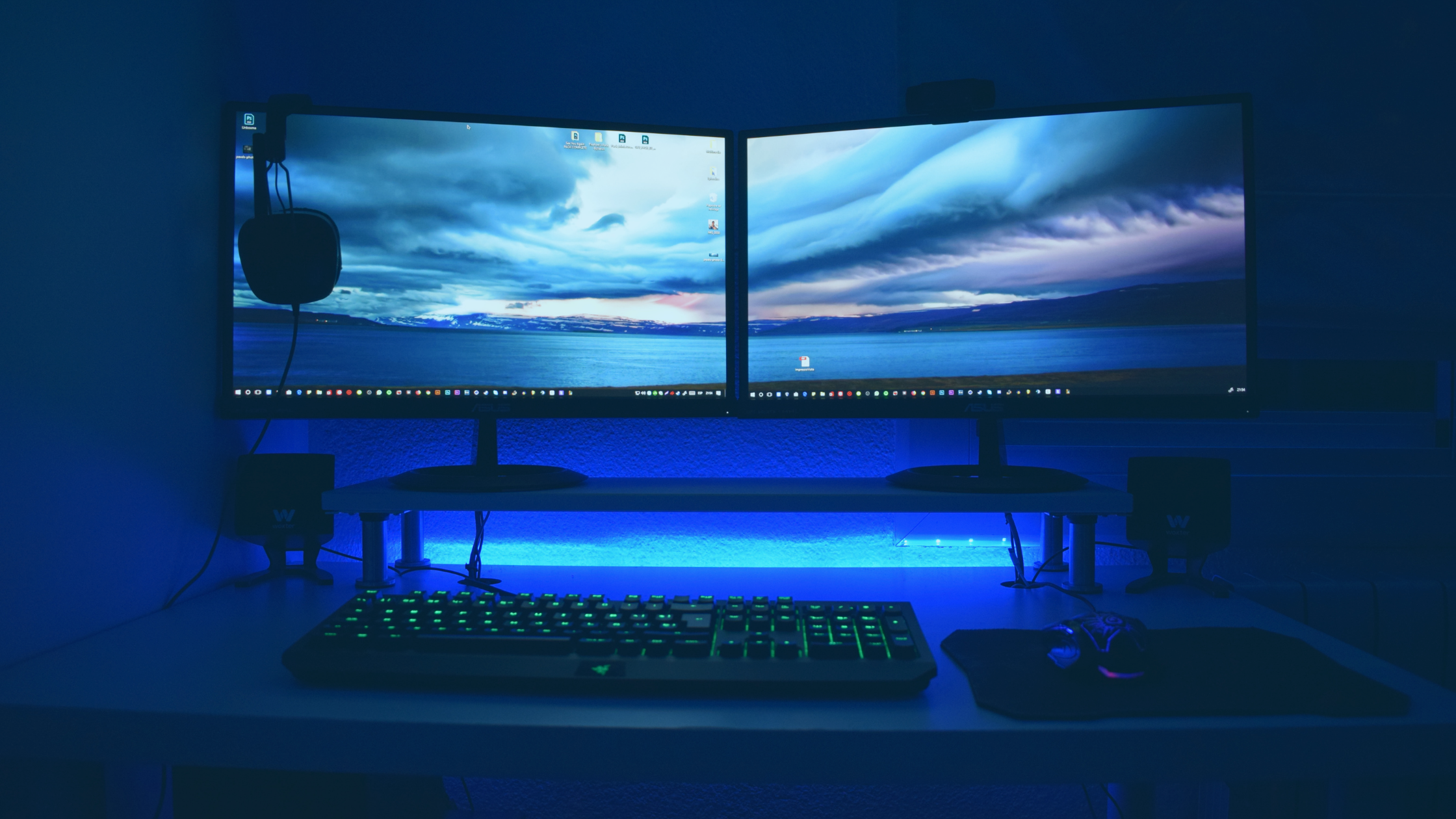 Setup com dois monitores curvados, sobre a lateral de um deles, há um headset.